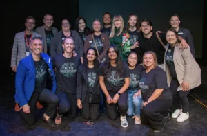 Image shows group of people smiling on a stage.